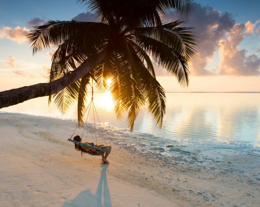 person swinging on hammock hanged on coconut tree near sea