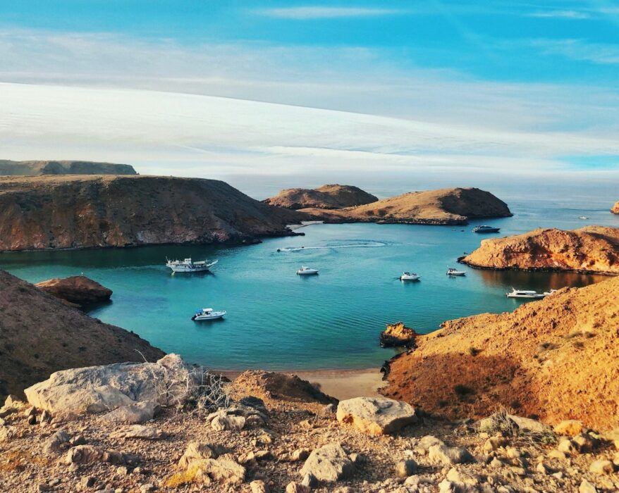 brown and green rock formation on blue sea under blue sky during daytime