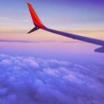 person in a plane flying at high altitude taking photo of left airplane wing during daytime