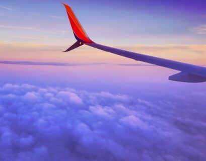 person in a plane flying at high altitude taking photo of left airplane wing during daytime