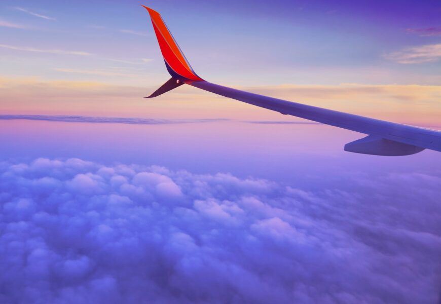 person in a plane flying at high altitude taking photo of left airplane wing during daytime