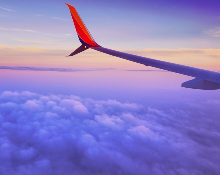 person in a plane flying at high altitude taking photo of left airplane wing during daytime